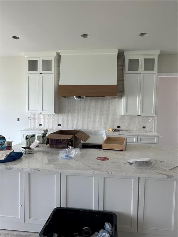 17321 Bluejacket St, Overland Park, KS 66221 - kitchen featuring backsplash, light stone counters, glass insert cabinets, white cabinetry, and recessed lighting
