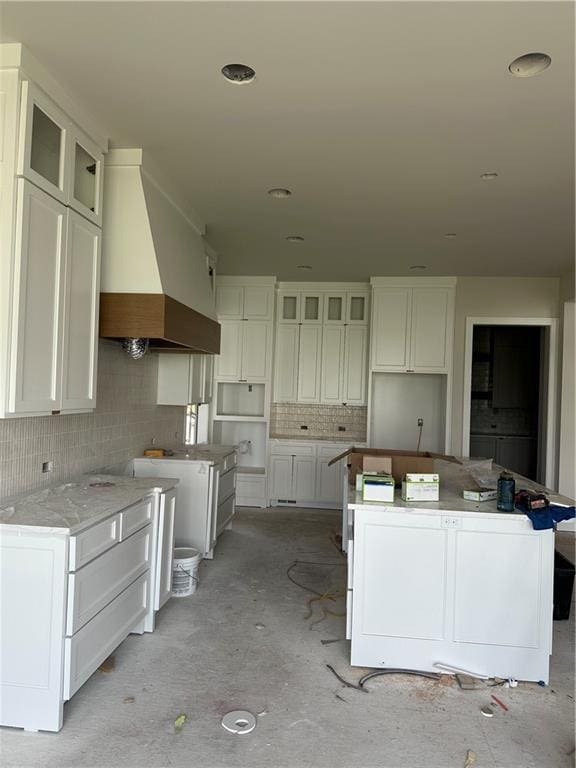 17321 Bluejacket St, Overland Park, KS 66221 - kitchen featuring custom range hood, a kitchen island, decorative backsplash, and white cabinetry