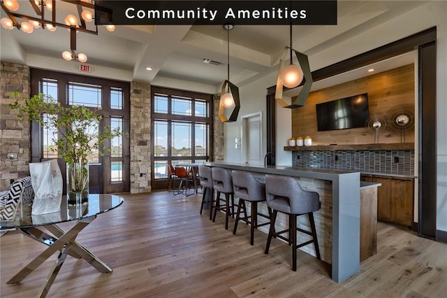 17321 Bluejacket St, Overland Park, KS 66221 - kitchen featuring brown cabinetry, backsplash, light wood finished floors, a breakfast bar area, and a towering ceiling