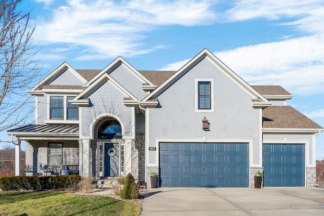 view of front of property with a shingled roof, covered porch, a garage, stone siding, and driveway