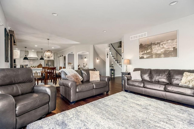 living room featuring stairway, wood finished floors, visible vents, and arched walkways