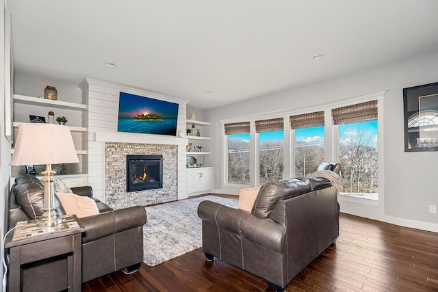 living area with baseboards, wood-type flooring, and a glass covered fireplace