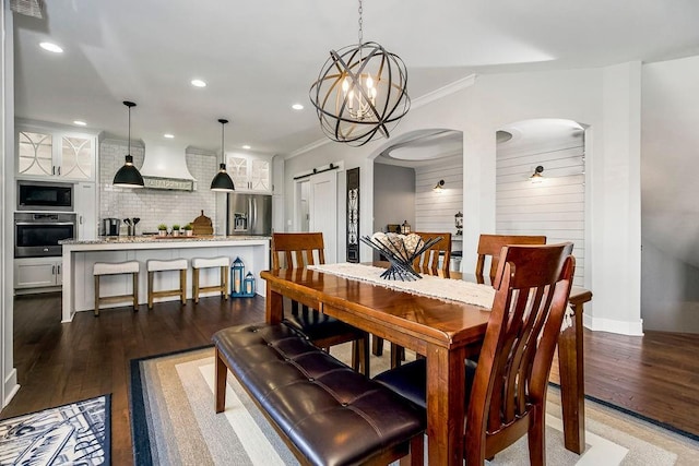 dining space featuring wood finished floors, recessed lighting, a barn door, arched walkways, and crown molding