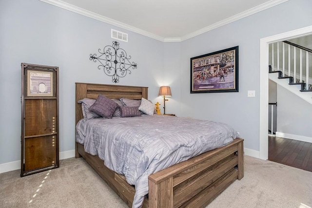 bedroom with baseboards, visible vents, carpet floors, and ornamental molding