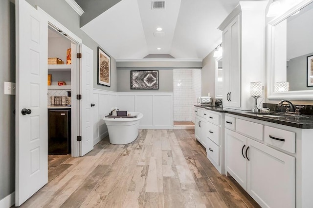 full bathroom featuring visible vents, a shower stall, lofted ceiling, wainscoting, and wood finished floors