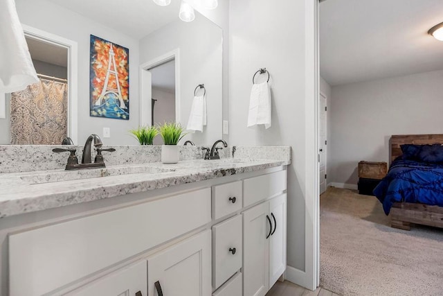 bathroom with double vanity, baseboards, and a sink