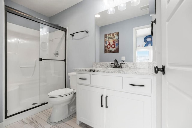 bathroom featuring visible vents, a stall shower, toilet, and vanity