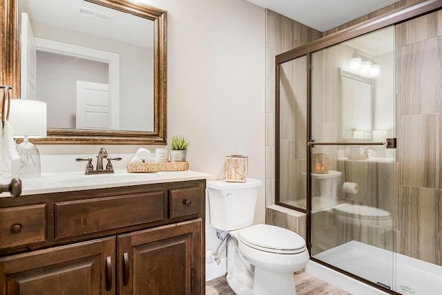 bathroom featuring visible vents, vanity, toilet, and a shower stall