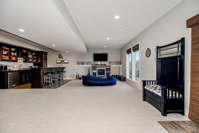 carpeted living room featuring visible vents, recessed lighting, a fireplace, indoor wet bar, and baseboards