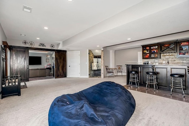 living room featuring wet bar, a barn door, recessed lighting, and visible vents