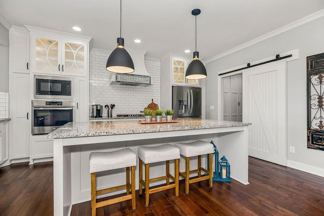 kitchen featuring ornamental molding, appliances with stainless steel finishes, white cabinetry, a barn door, and tasteful backsplash