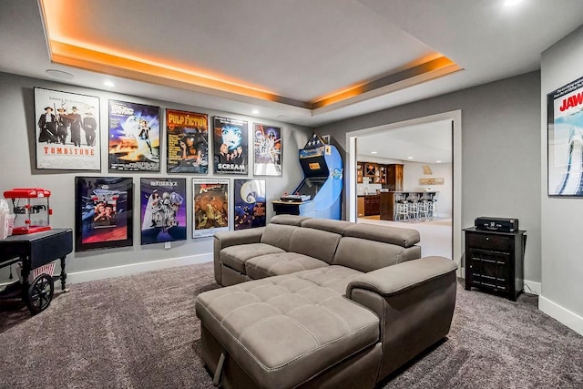 carpeted cinema room with a raised ceiling and baseboards