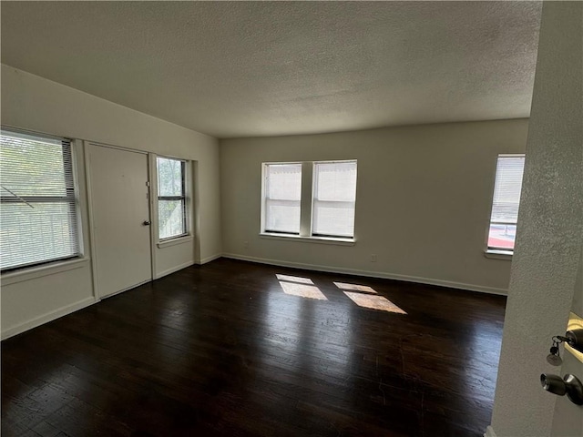 empty room featuring baseboards, a textured ceiling, and hardwood / wood-style floors