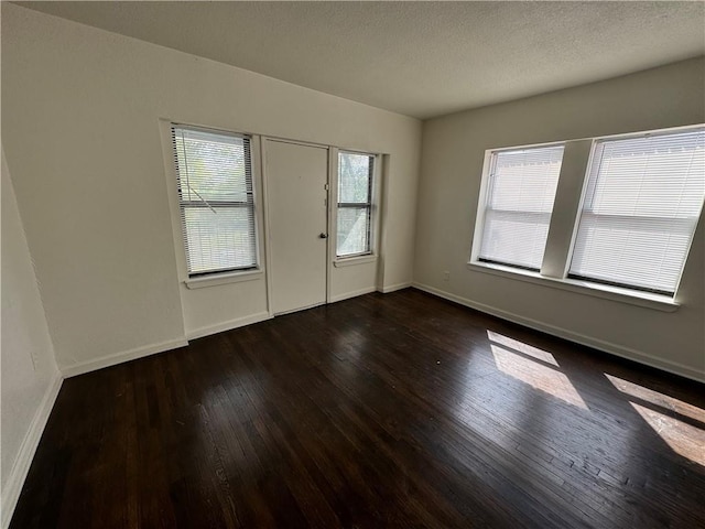 interior space featuring dark wood-style flooring, a textured ceiling, and baseboards