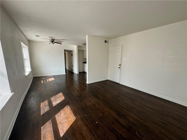 3112 Benton Blvd, Kansas City, MO 64128 - unfurnished living room featuring a textured ceiling, ceiling fan, visible vents, baseboards, and dark wood finished floors
