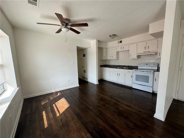 3112 Benton Blvd, Kansas City, MO 64128 - kitchen with white range with electric cooktop, dark countertops, visible vents, dark wood-type flooring, and under cabinet range hood