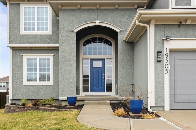 view of exterior entry featuring a garage and stucco siding