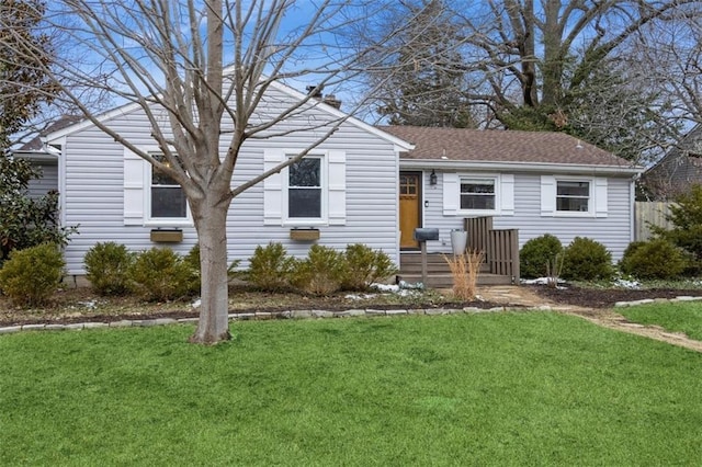 ranch-style home with a front lawn and roof with shingles