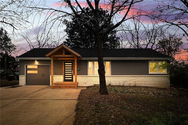 view of front of property with stone siding, driveway, and an attached garage