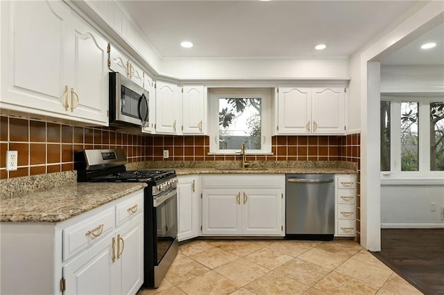 kitchen with stainless steel appliances, backsplash, a sink, and white cabinets