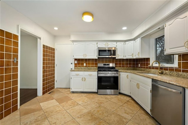 kitchen with stainless steel appliances, white cabinetry, a sink, and decorative backsplash