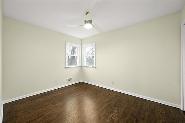 spare room featuring a ceiling fan, baseboards, visible vents, and dark wood-style flooring