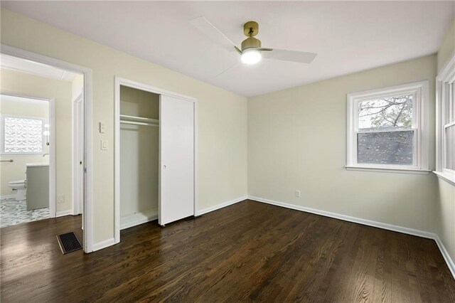 unfurnished bedroom featuring baseboards, visible vents, dark wood finished floors, and a closet