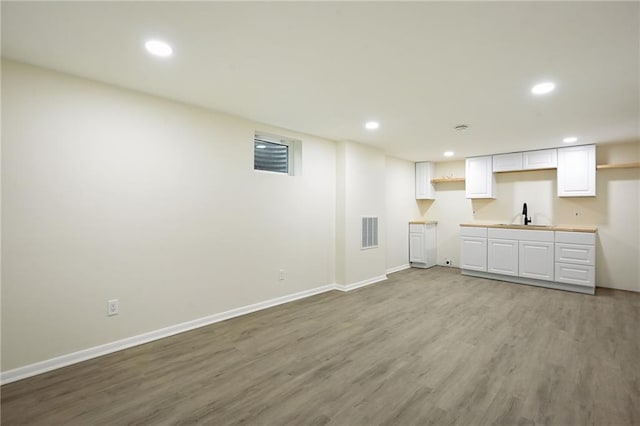 interior space with recessed lighting, visible vents, a sink, and wood finished floors