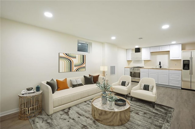 living room featuring baseboards, visible vents, wood finished floors, and recessed lighting