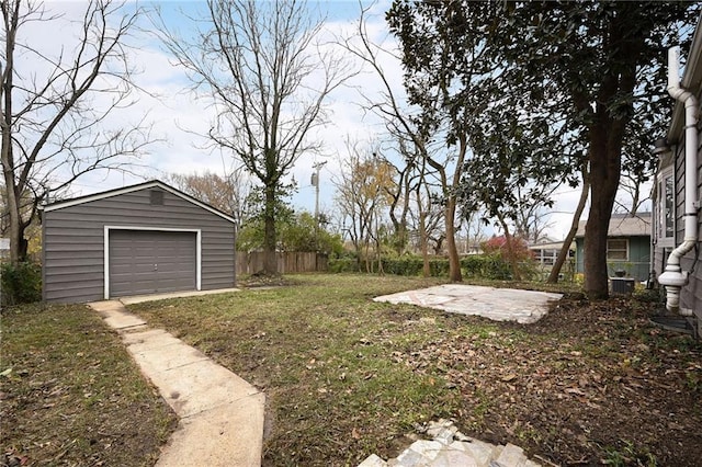 view of yard featuring an outbuilding, driveway, a detached garage, and fence