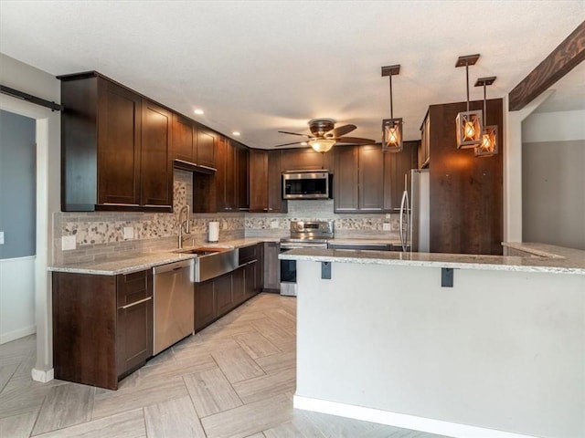 kitchen with stainless steel appliances, light stone countertops, dark brown cabinets, and decorative backsplash