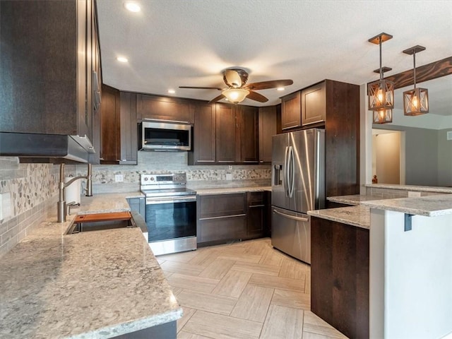 kitchen featuring backsplash, appliances with stainless steel finishes, ceiling fan, and a sink