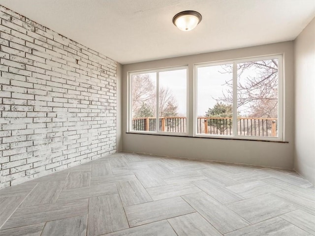 unfurnished room featuring brick wall