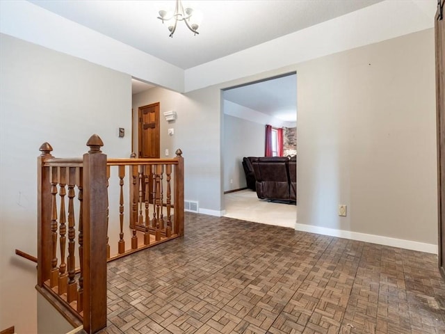 hall with baseboards, an upstairs landing, and visible vents