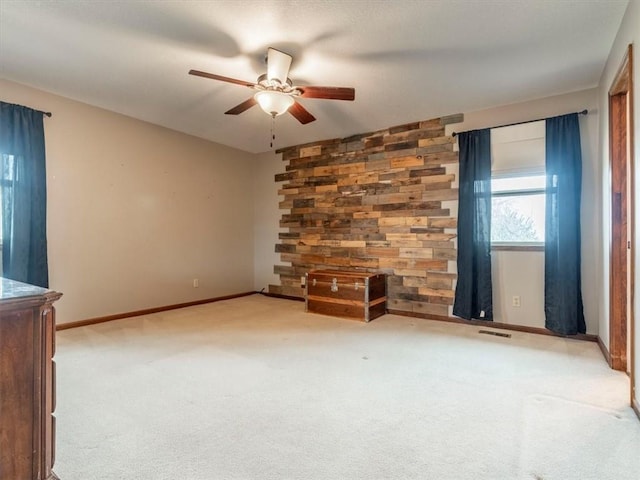 empty room featuring visible vents, carpet flooring, baseboards, and ceiling fan