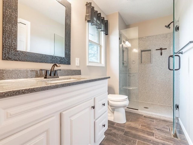 full bath with a stall shower, toilet, vanity, and wood tiled floor