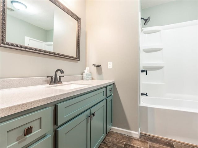 full bath featuring wood finish floors, shower / washtub combination, vanity, and baseboards