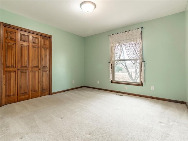 unfurnished bedroom with visible vents, baseboards, and light colored carpet