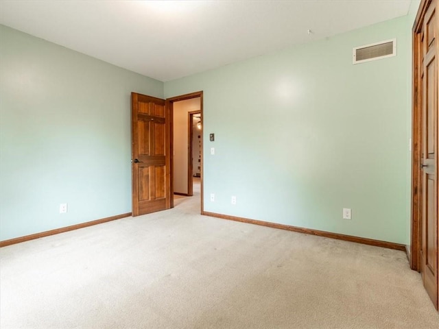 spare room with baseboards, visible vents, and light carpet