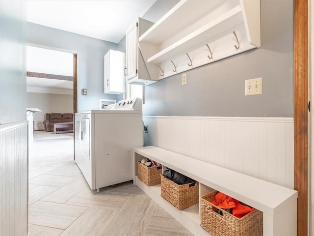 clothes washing area with cabinet space, a wainscoted wall, and washer and dryer