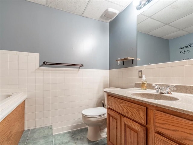 full bathroom featuring tile patterned floors, a drop ceiling, tile walls, and vanity