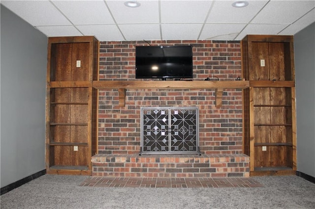 unfurnished living room featuring a drop ceiling, baseboards, and carpet floors