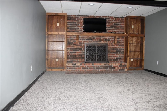 unfurnished living room featuring carpet, a fireplace, baseboards, and a paneled ceiling