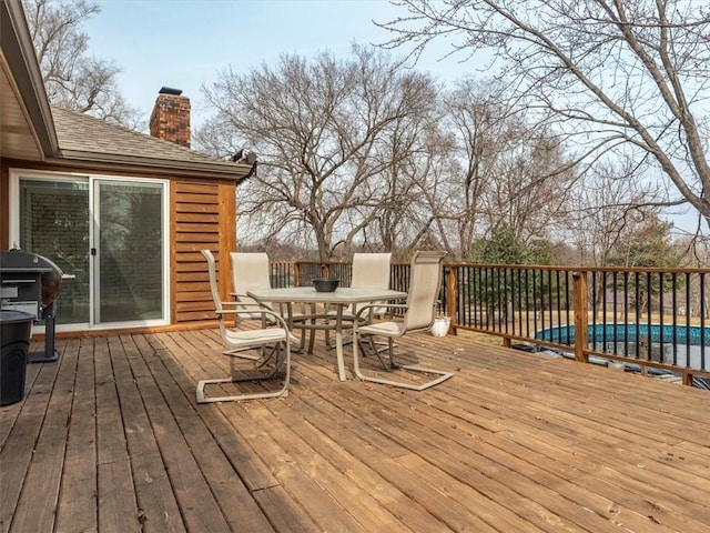 deck featuring outdoor dining space, a fenced in pool, and a grill