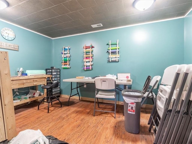 office space with baseboards, wood finished floors, visible vents, and ornamental molding