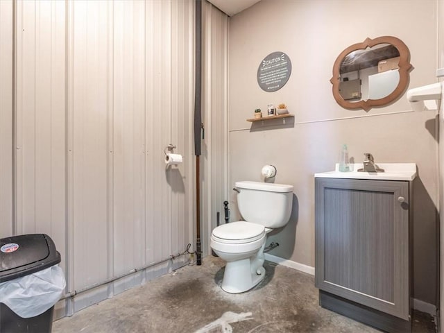 bathroom featuring unfinished concrete floors, toilet, vanity, and baseboards