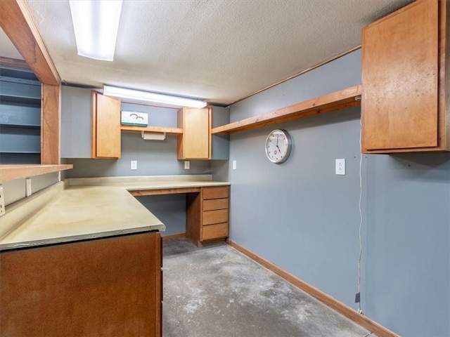 kitchen featuring concrete floors, baseboards, built in desk, a textured ceiling, and open shelves