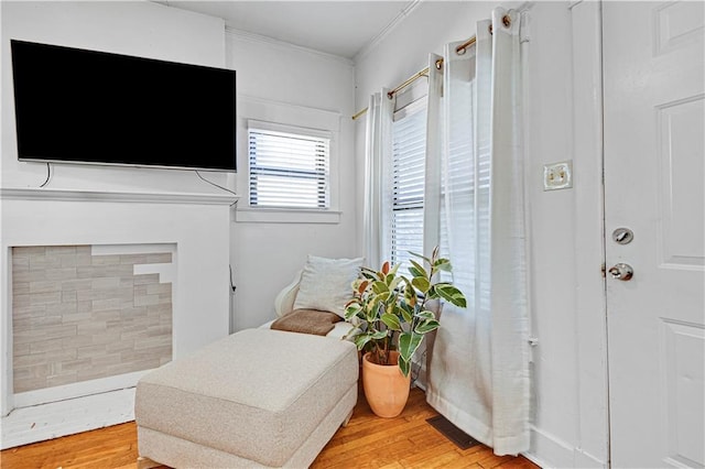 living area featuring visible vents, light wood finished floors, and ornamental molding