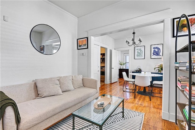 living area with light wood finished floors, baseboards, crown molding, and an inviting chandelier