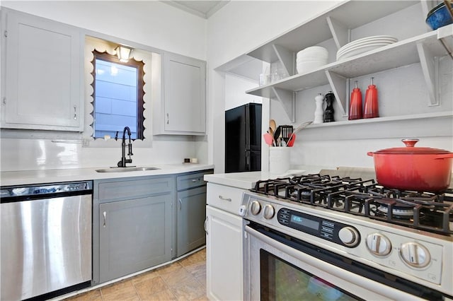 kitchen featuring open shelves, appliances with stainless steel finishes, light countertops, and a sink